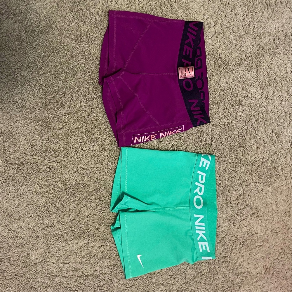 2 pairs of small nike pros in purple and green
